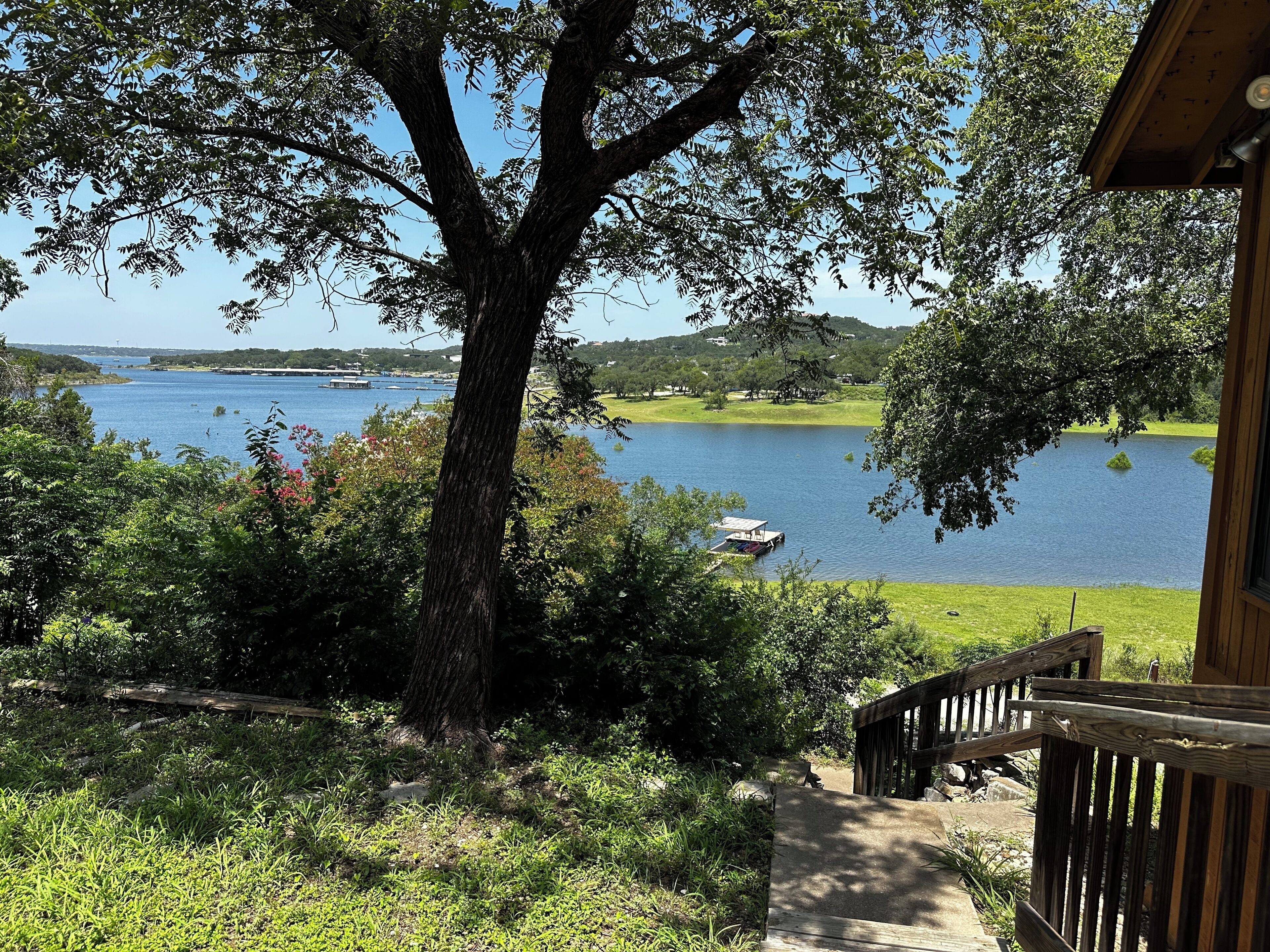 Une vue sur un lac avec un quai, entouré d’arbres et d’un bâtiment en bois doté d’une terrasse.