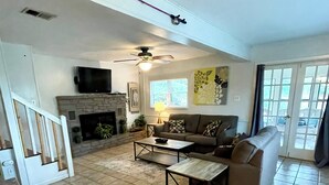 A living room with a fireplace, a sofa, a coffee table, and a television. - Lake Travis Waterfront Home - 4 Bed, 2 Bath, spectacular views, & private dock (Austin)