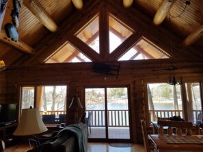 A cozy cabin with a wooden interior, large windows, and a television. - Relax at Perch Lake Lodge!   (Lake Station)
