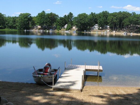 A calm lake with a dock and a boat.