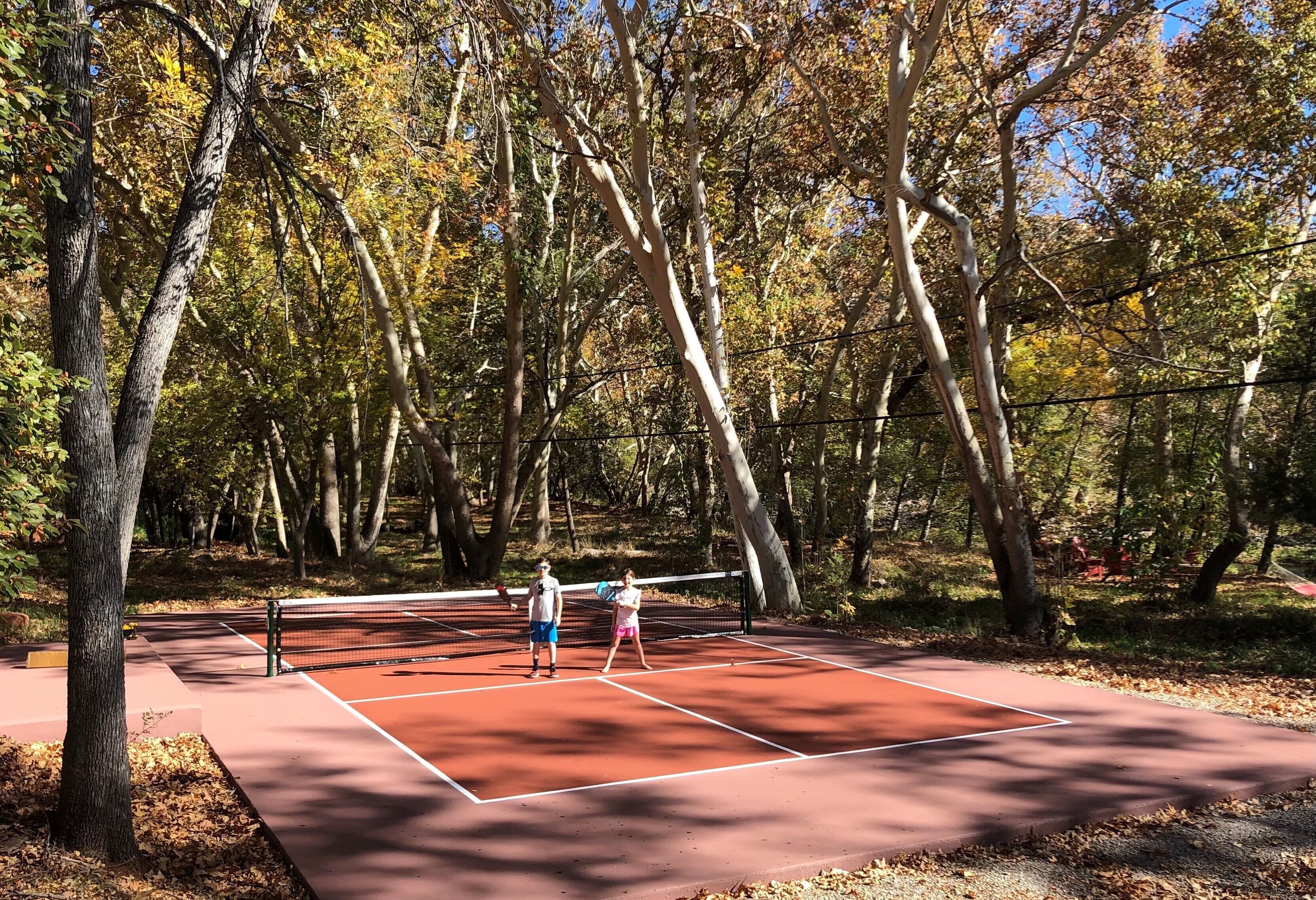 An outdoor tennis court surrounded by trees.