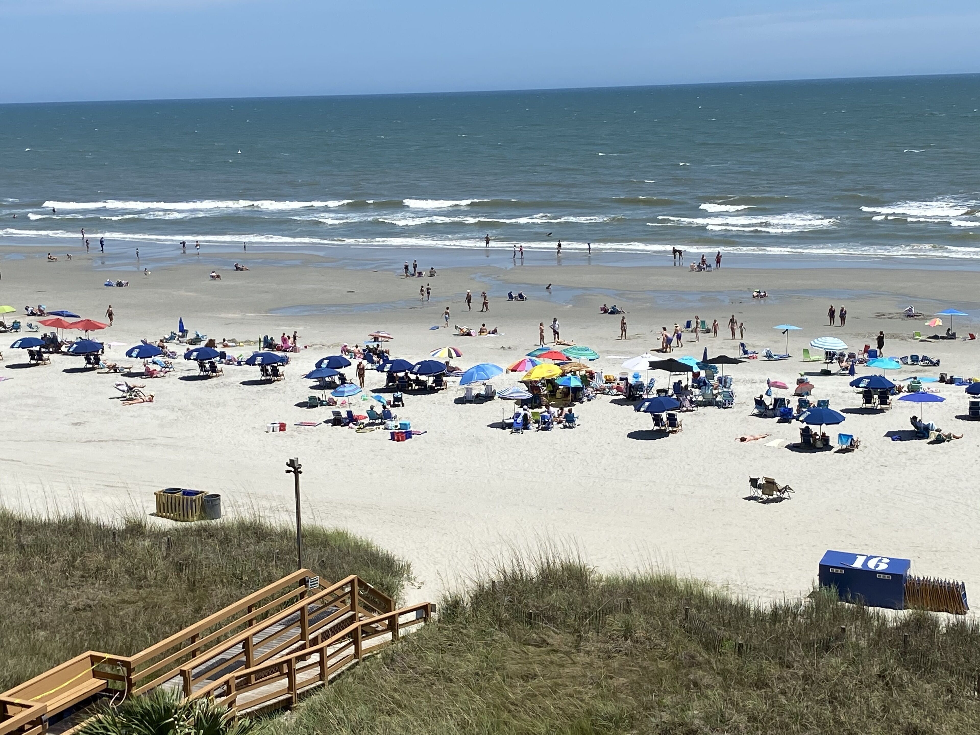 Une plage avec de nombreux parasols et beaucoup de monde.