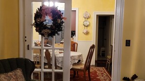 Una sala de estar con un sillón verde, un comedor con mesa y sillas, y un pasillo que lleva a otra habitación.