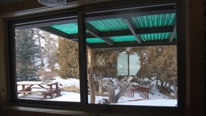 A window with a view of a snowy outdoor area, including a wooden picnic table and a covered seating area.
