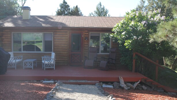 A log cabin with a porch, outdoor seating, and a gravel pathway leading to the entrance.