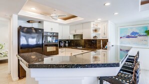 A modern kitchen with a central island, white cabinetry, and a ceiling fan. - Amazing ocean front, ground floor condo in Mission Beach! Book now and save! (San Diego)