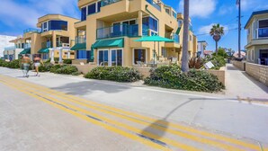 A multi-story hotel with balconies, outdoor seating, and a clear blue sky. - Amazing ocean front, ground floor condo in Mission Beach! Book now and save! (San Diego)