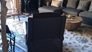 Un salon chaleureux avec une cheminée en pierre, un canapé, une table basse et un plafond en bois.
