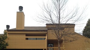Une maison en bois à deux étages, dotée d’un porche à l’avant et d’une cheminée.