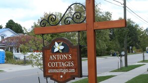 Een houten bordje met de tekst 'ANTON'S COTTAGES' en een websiteadres.