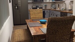 Eine moderne Küche mit Einbaukühlschrank, Mikrowelle und Herd. Ein Esstisch mit Korbstühlen und einer blauen Schüssel.