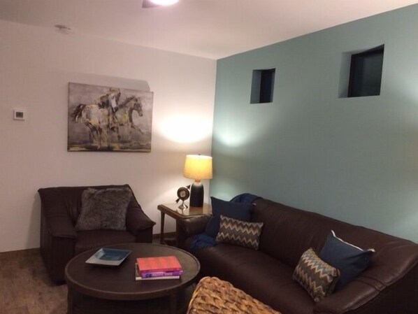 Ein Wohnzimmer mit einer braunen Ledersofa, einem runden Couchtisch und einem Gemälde an der Wand.