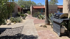 Eine Terrasse mit Grill, Kiesweg und verschiedenen Kakteen und Sukkulenten.