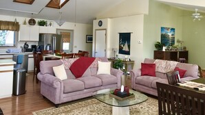 A spacious living area with a high ceiling, a dining table, two sofas, and a kitchen in the background. - Ocean View Apartment Along Maine's Scenic Penobscot Bay (Belfast)