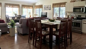 A spacious living area with a dining table surrounded by wooden chairs, a sofa, and a TV. - Ocean View Apartment Along Maine's Scenic Penobscot Bay (Belfast)