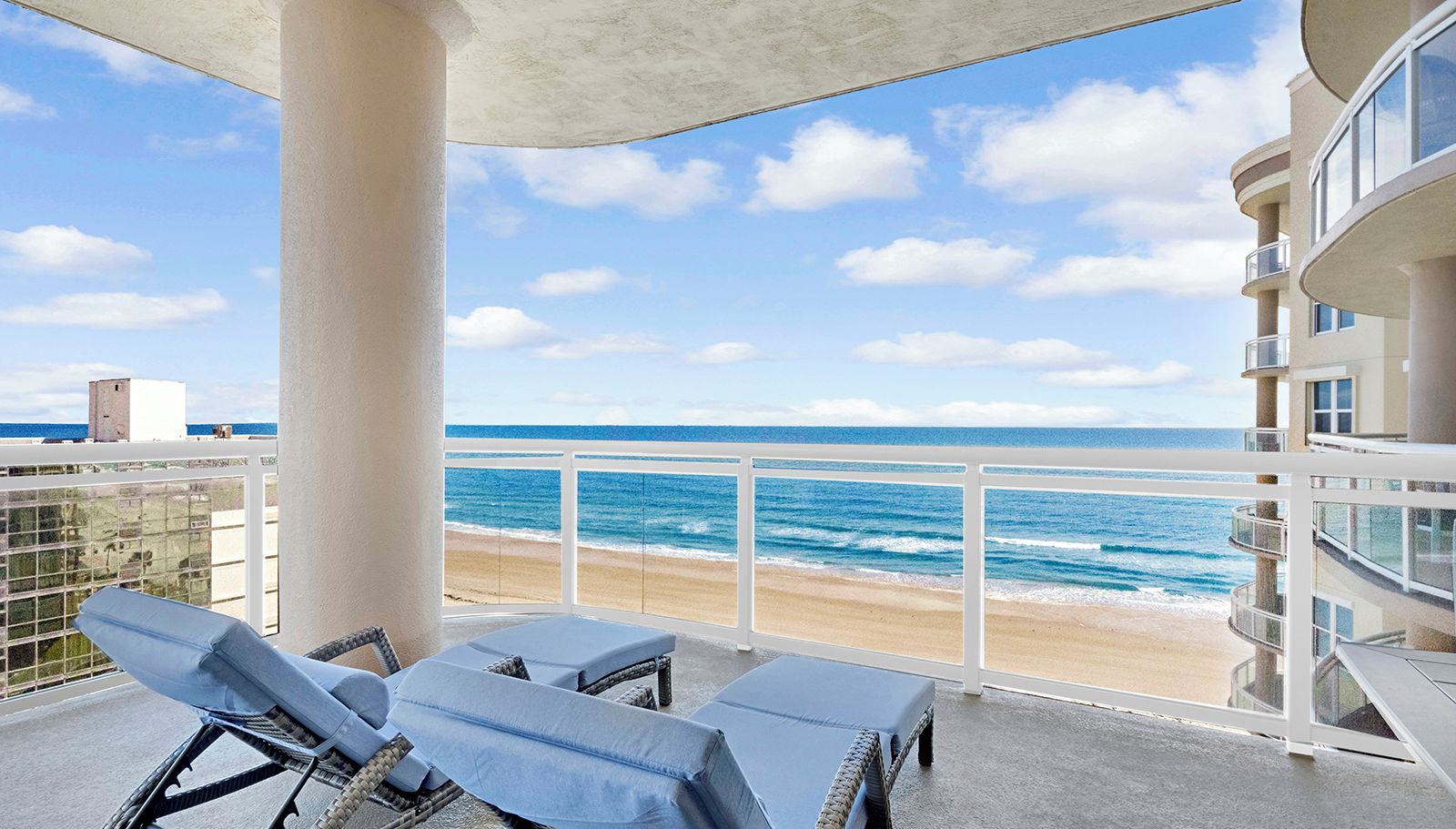 A balcony with a view of the beach and ocean.