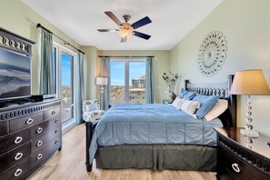 Ein Schlafzimmer mit Bett, Kommode, Fernseher und Blick auf die Stadt.