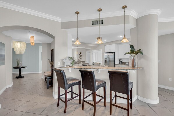 A spacious kitchen with a central island, bar stools, pendant lighting, and a chandelier.