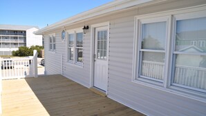 A white building with a wooden deck, multiple windows, and a white fence. - Ocean view, Pet Friendly house with private swimming pool! Sleeps 10. (North Myrtle Beach)