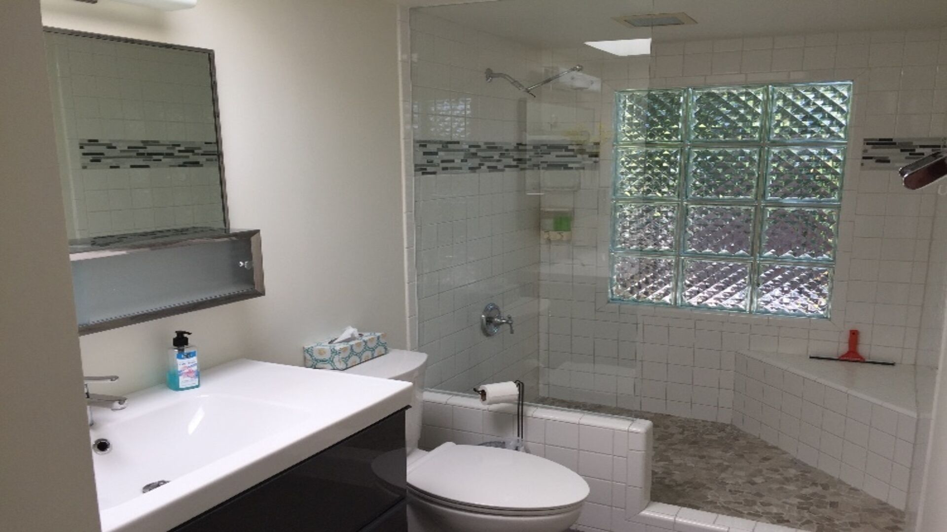 A bathroom with a white sink, toilet, and shower area.