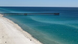 Una spiaggia con un molo che si protende nell'oceano, cieli sereni e acque calme.