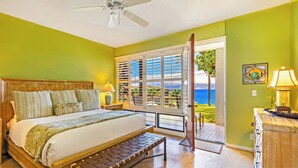 Ein Schlafzimmer mit Bett, Bank, Nachttisch, Lampe und Meerblick.