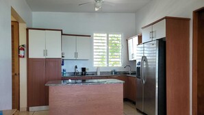 A kitchen with a central island, stainless steel appliances, and a ceiling fan.