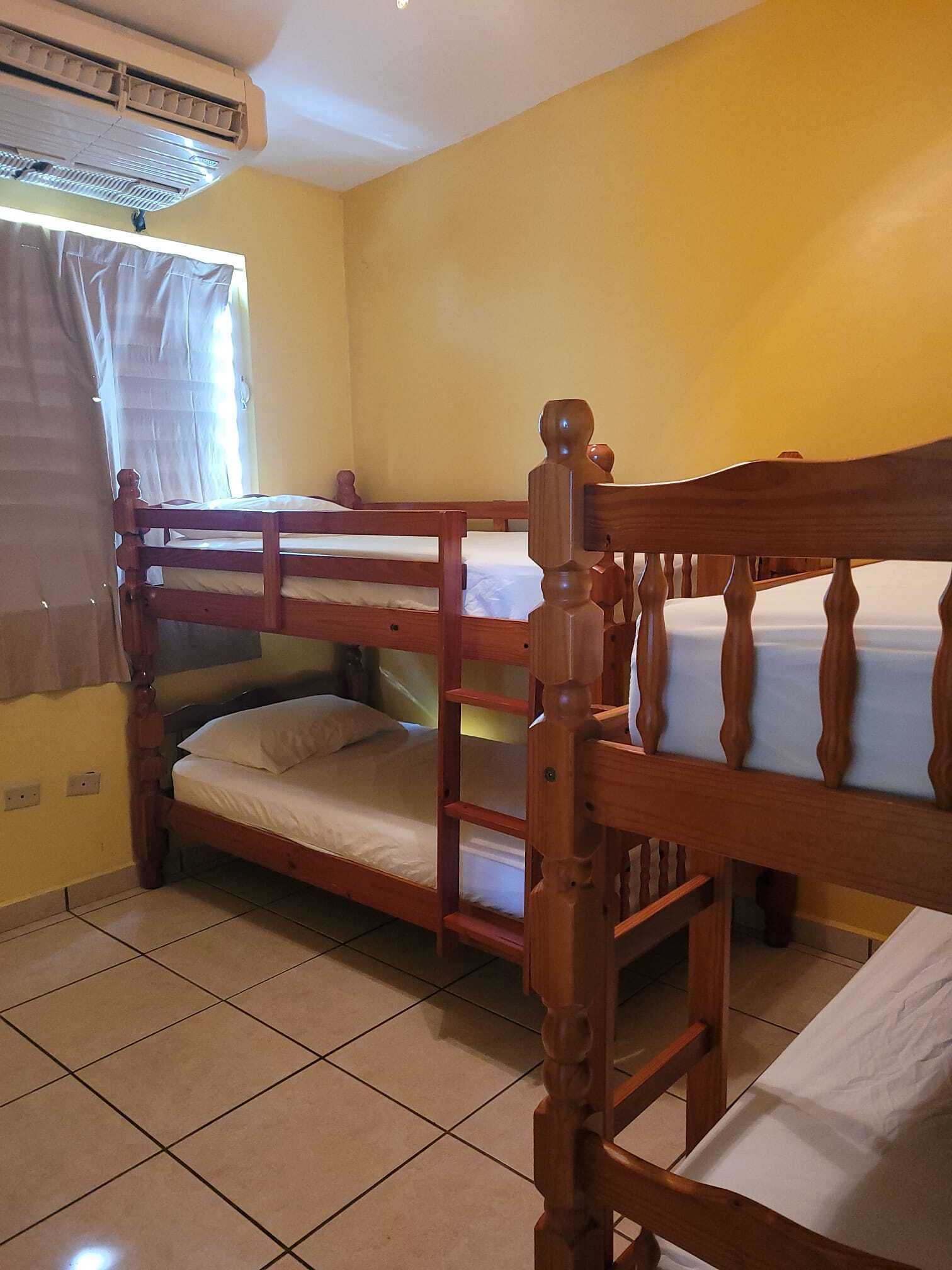 A room with bunk beds, a window with curtains, and an air conditioning unit.