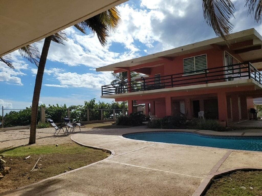 A two-story building with a swimming pool, outdoor seating, and a covered area.