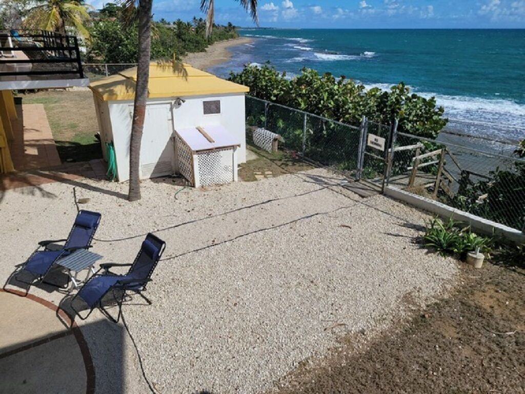 Una propiedad frente a la playa con un área de patio, dos sillones de descanso y vista al océano.