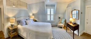 Relax in this serene space with a large bed, bedside tables, and a comfortable chair by the window.