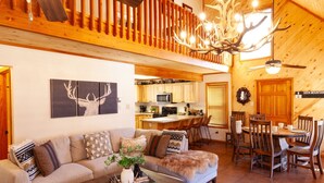 A cozy cabin interior with a dining area, kitchen, and living room. - Deer Mountain Lodge - High-End Home - In Town - Hot Tub - Free WiFi - Washer/Dry (Red River)