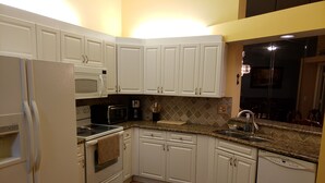 A kitchen with white cabinets, a microwave, a toaster, a sink, and a dishwasher. - Centrally Located in Beautiful Naples (NAPLES)