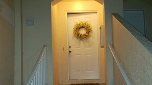 A staircase leading to a door with a wreath, white railings, and a textured wall. - Centrally Located in Beautiful Naples (NAPLES)