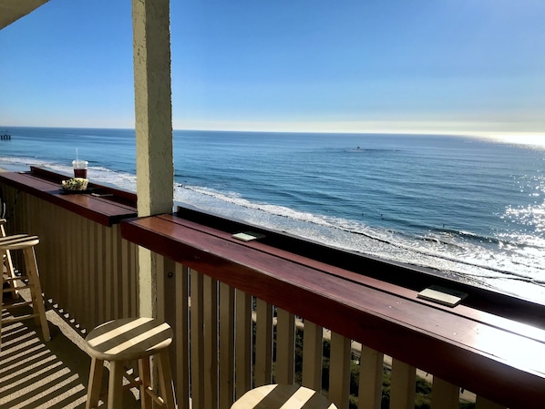 Ein Balkon mit Holzbalkonen, der Blick auf einen Strand bietet.