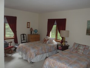 Une chambre avec deux lits, une commode, une lampe, un globe terrestre et une fenêtre avec des rideaux.