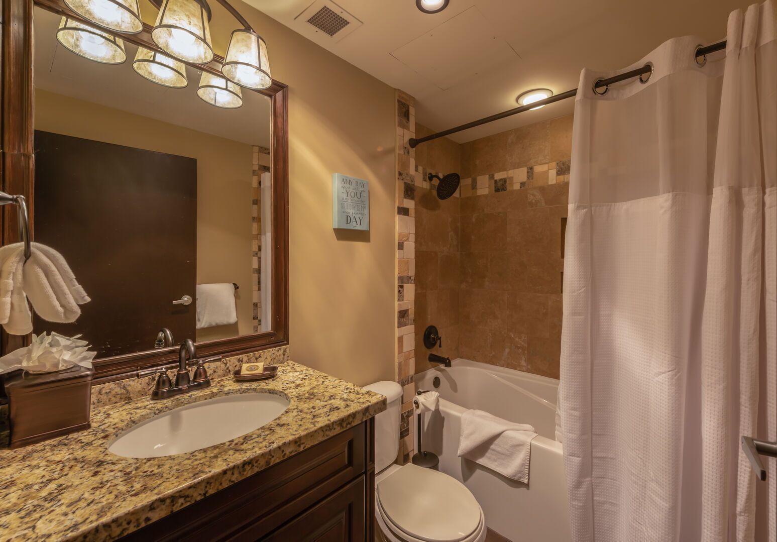 A bathroom with two sinks, a mirror, a shower, and a toilet.