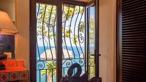 A room with a view of a rocky coastline through a metal gate.
