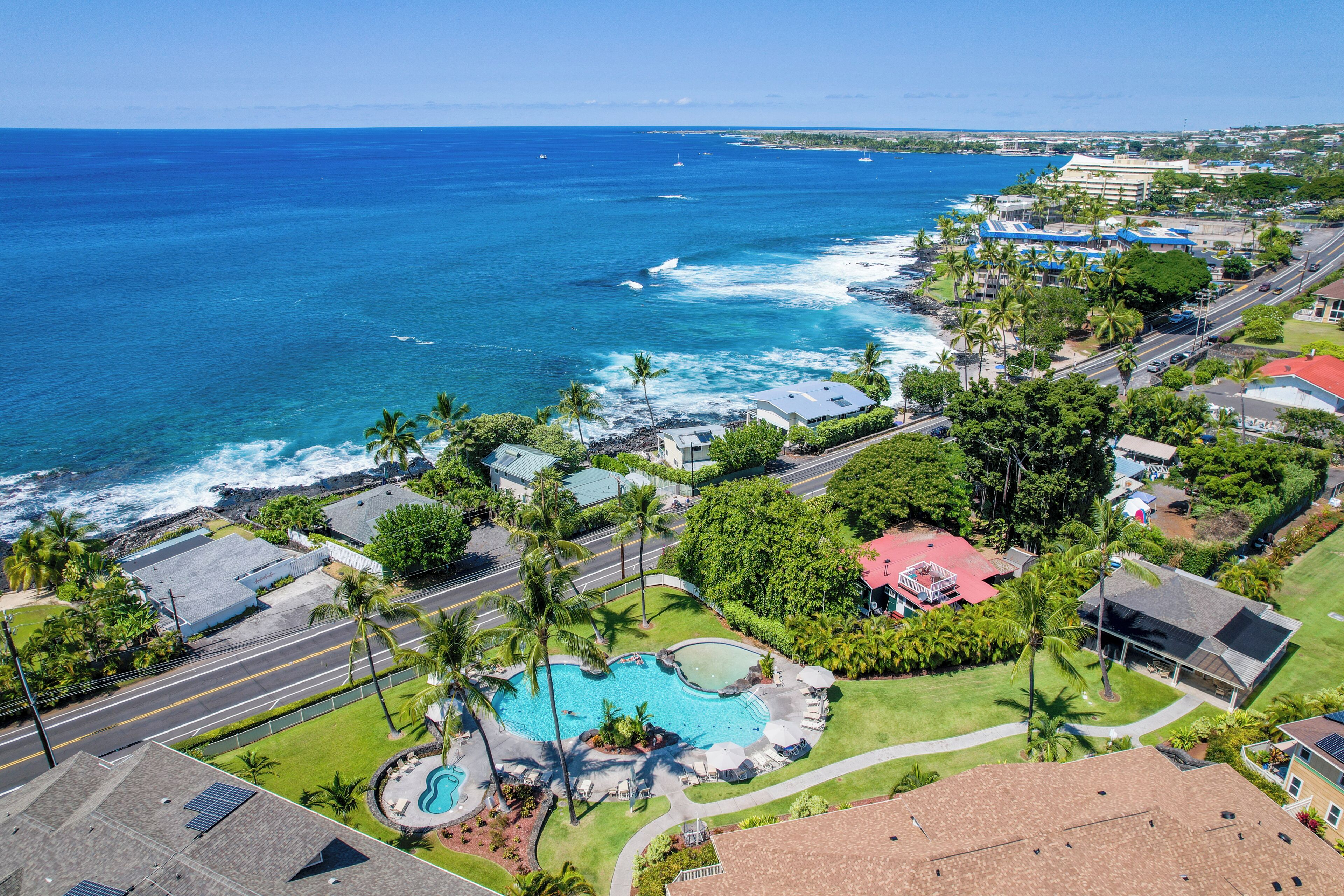 A coastal property with a swimming pool, a road, and a view of the ocean.