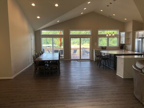 A spacious kitchen with a large island, a dining area with a table and chairs, and a view of the outdoors through large sliding glass doors.