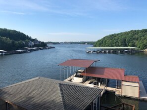 A riverside dock with a covered seating area and a boat house.