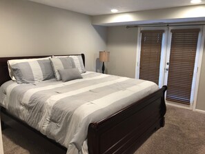 A bedroom with a bed, a nightstand, a lamp, and a closet with sliding doors.