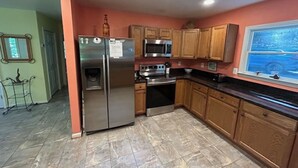 A kitchen with a refrigerator, microwave, oven, and wooden cabinets. - Waterfront home on a quiet cove mid-lake! 4 kayaks, hot tub, and dog friendly!  (Mineral)
