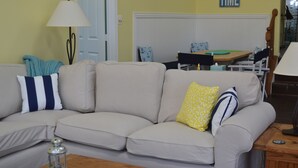 A living room with a beige sofa, a wooden coffee table, a lamp, and a dining table with chairs. - Waterfront home on a quiet cove mid-lake! 4 kayaks, hot tub, and dog friendly!  (Mineral)