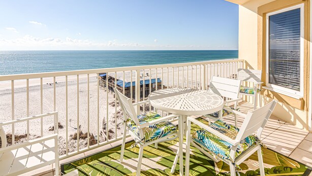 A balcony with a table and chairs, overlooking a beach and the ocean. - Direct Gulf front View two bedroom, two bath totally refurbished. (Gulf Shores)