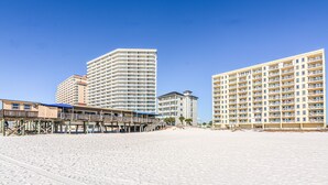 A beachfront hotel with multiple floors, a wooden boardwalk, and a clear blue sky. - Direct Gulf front View two bedroom, two bath totally refurbished. (Gulf Shores)