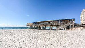 A beachfront hotel with multiple balconies and a pier extending into the ocean. - Direct Gulf front View two bedroom, two bath totally refurbished. (Gulf Shores)