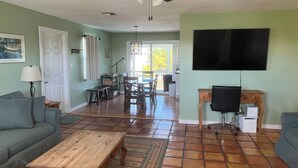Ein Wohnzimmer mit Couch, Fernseher, Holztisch und Deckenventilator.