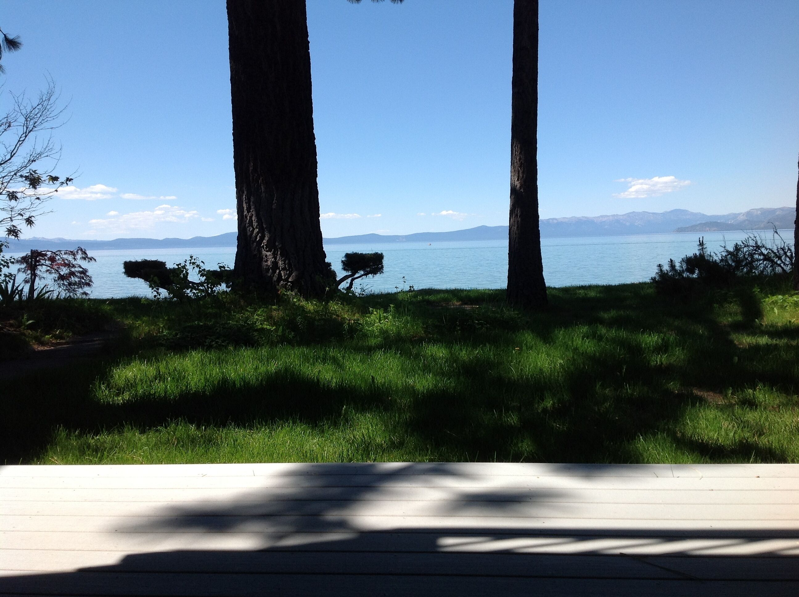 A deck with a view of a lake and mountains in the distance.