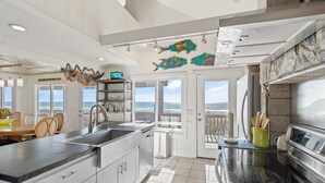 A modern kitchen with a large island, a view to the ocean, and decorative fish wall art. - "Ocean Kiss" - Oceanfront Home, 6 Bedrooms / 4 Bathrooms (Holden Beach)